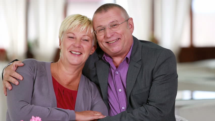 Happy senior couple embracing and smiling at the camera