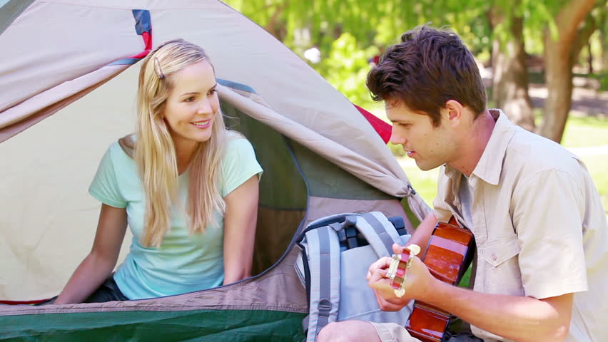 Man singing a song to his girlfriend while camping