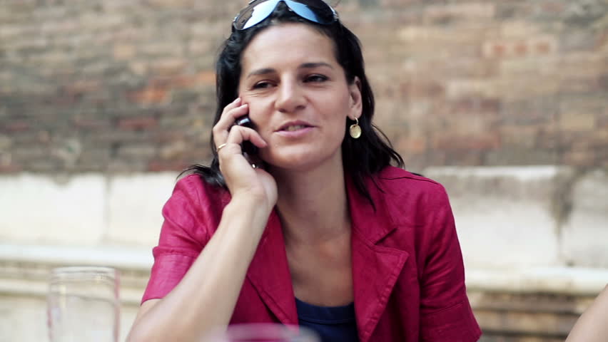Two women sitting in the restaurant and chatting on cellphone, steadycam shot
