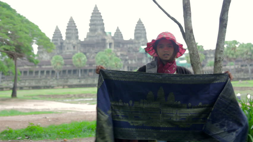 ANGKOR WAT - JUNE 2012: local seller shows her products in front of the famous temple. Angkor wat is the largest Hindu temple complex in the world.