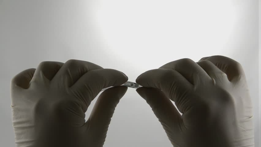 surgeon's hands stretching, compressing and bending the braided self-expanding nitinol endovascular stent