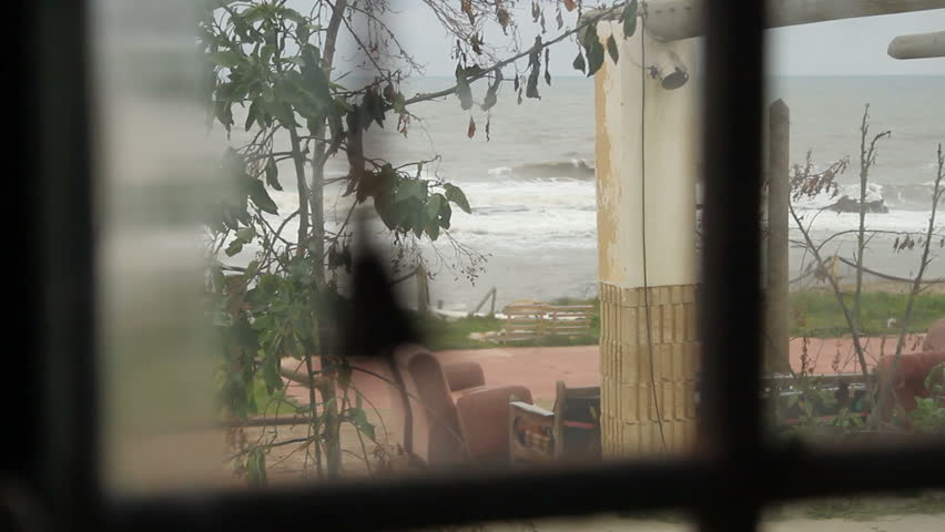 Decorative bell hanged on the window of a beach house - focus change from interior to exterior (waves)
