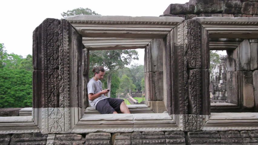 Caucasian tourist using mobile phone in Angkor