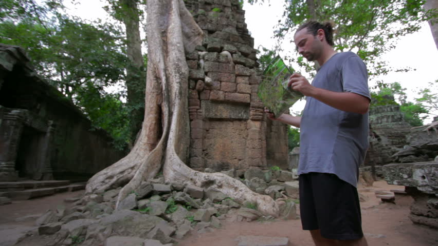 Visitor reading tourist information map in Ta Prohm temple, Angkor