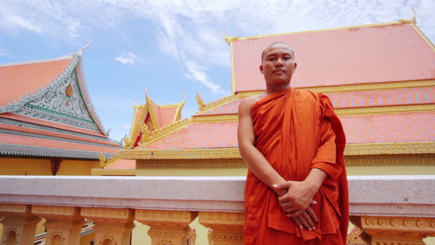 A kind Buddhist monk with orange robe pray in temple