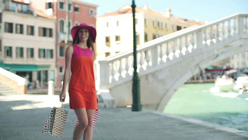 Rich woman in hat with shopping bugs in Venice
