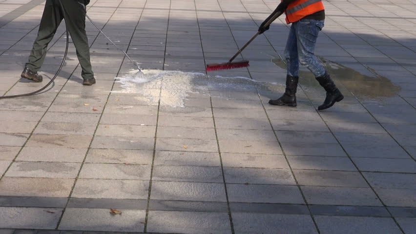 workers cleaning city square granite pavement