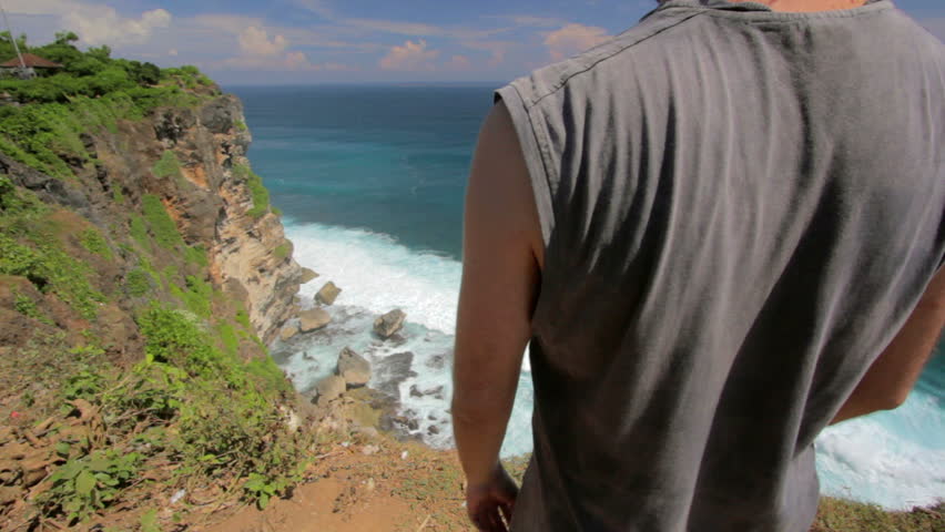 suicidal young man at the edge of cliff overlooking ocean