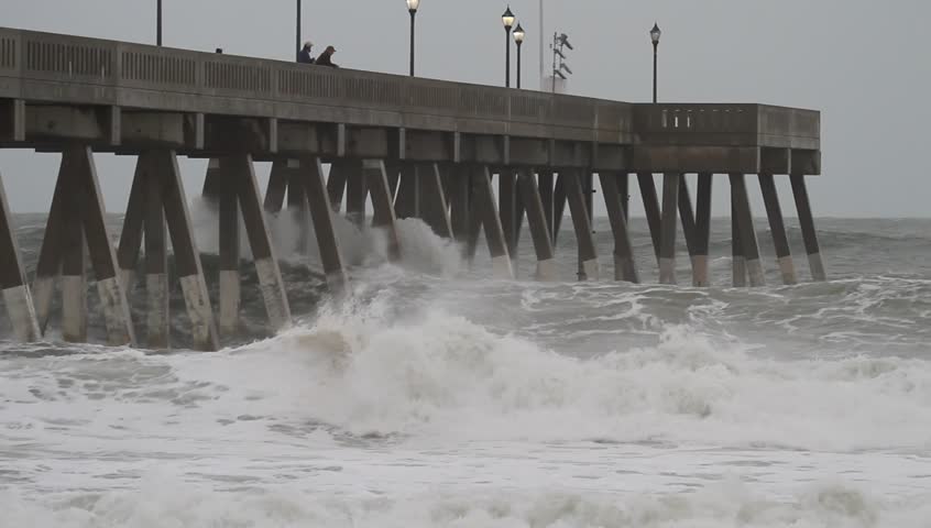 Wide Shot of Atlantic Ocean Waves Crash into Johnny Mercer Pier at Wrightsville Beach North Carolina as Hurricane Sandy Passes Along the Coast.  Waves spray up as they hit the pilings of the pier. 