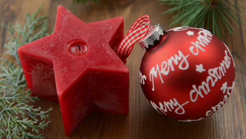 Christmas candle in star shape is lit with a match. In addition, a  pine twig and a Christmas ball  with "Merry Christmas" written on it. 