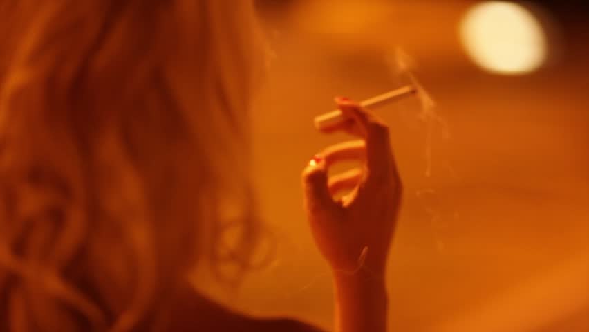Girl smoking beside a deserted city street at night.