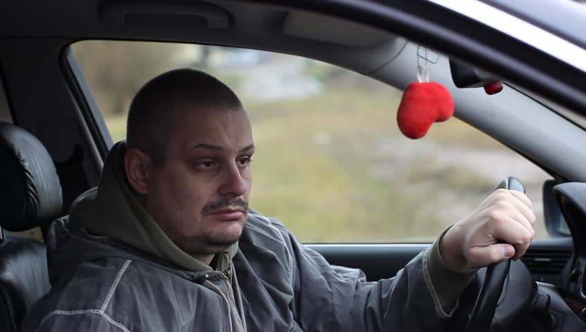 Depressed man drinking alcohol in car