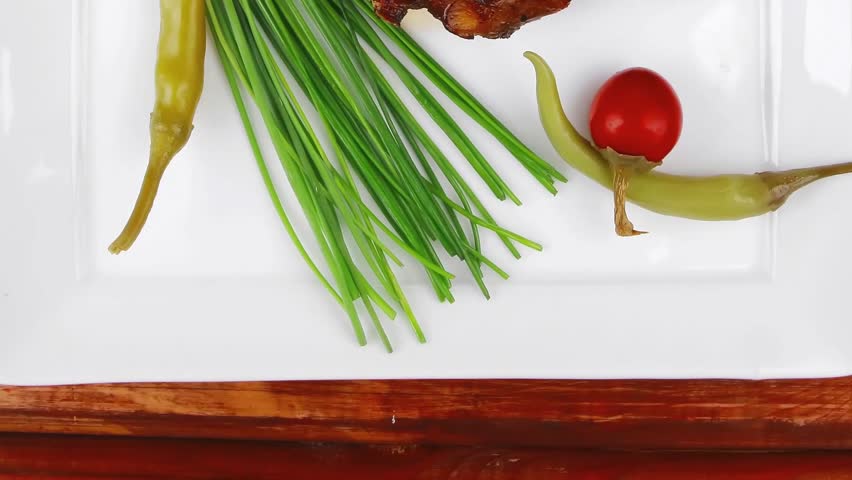 holiday dinner meat savory on wooden table: roast ribs on white plate with peppers lettuce tomato and chives