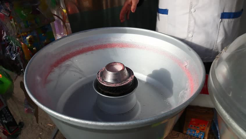 Cotton candy making in Bucharest, Romania. Strawberry flavor and red color. Daylight, outdoor, medium shot.

