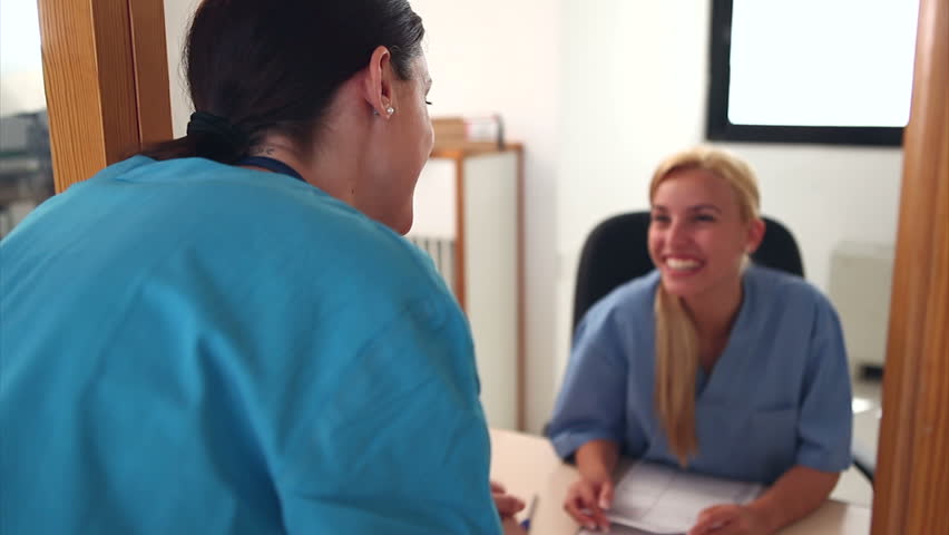 Intern speaking with a receptionist in hospital entrance