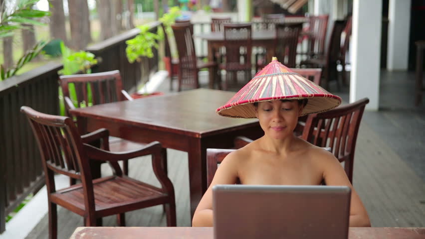Asian freelance business woman at cafe with laptop and colorful hat