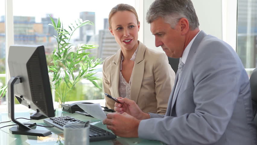 Two colleagues calculating bills in an office