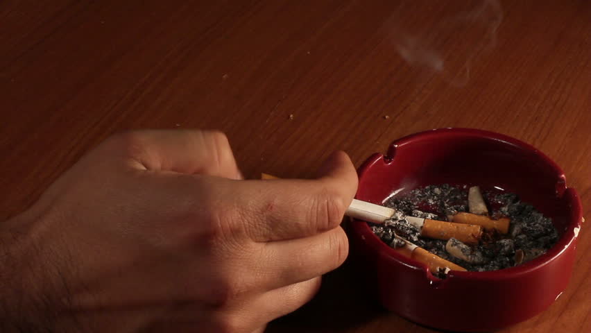 Detail of Male hand smoking Cigarette in ashtray