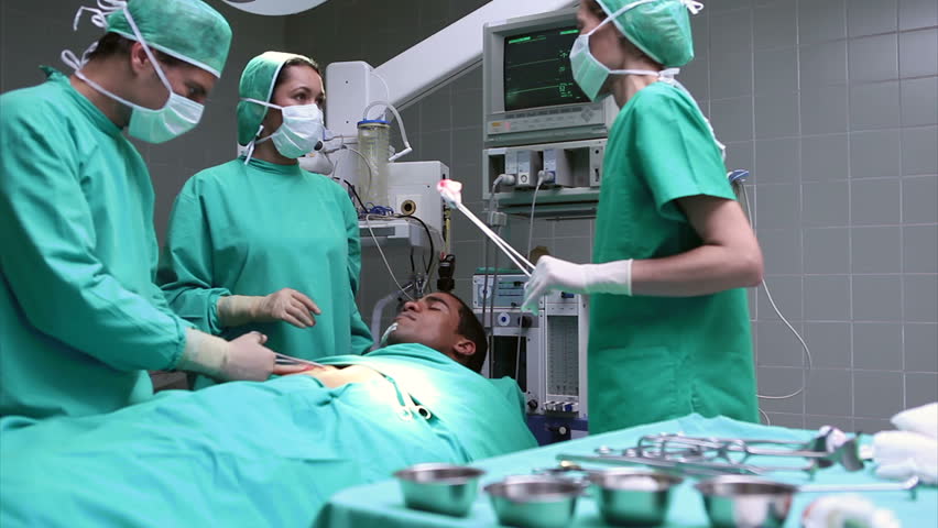 Team of surgeons working on an unconscious male patient in an operating theater