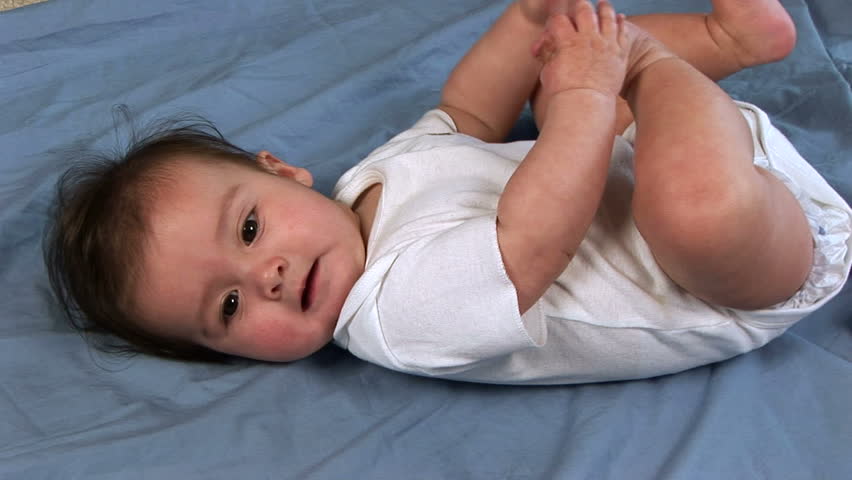 Close shot of a baby lying on a blanket on the floor