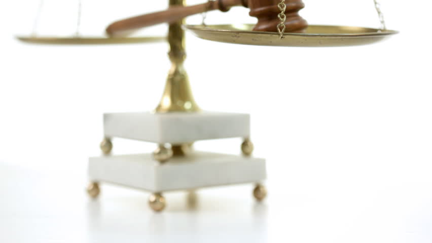 Rack focus on legal scales with gavel resting on them.