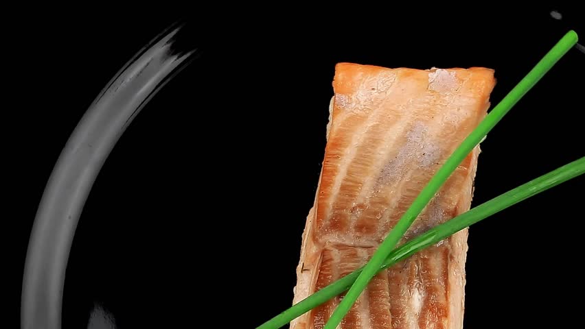 savory sea fish entree : roasted salmon fillet with green onion on black dish isolated over white background