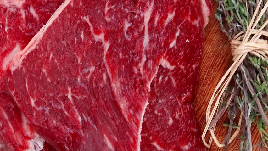 fresh raw beef meat fillet flesh with peppercorn and thyme ready to grill on wood figured old style board isolated over white background