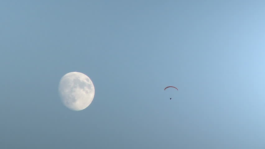 Paraglider sailing in sky with moon