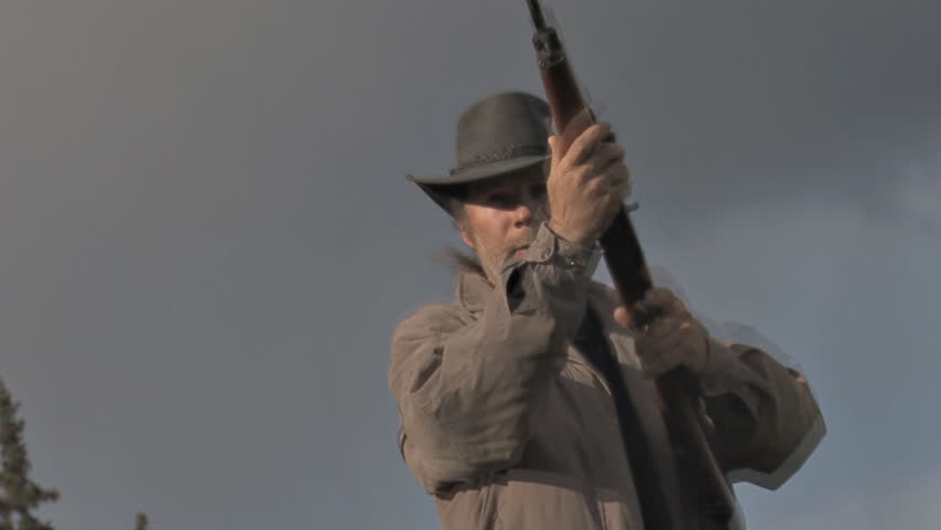 Sinister-looking man in a beat up black hat getting ready to shoot ... POV shot of the Unfortunate Victim. Track motion zoom.