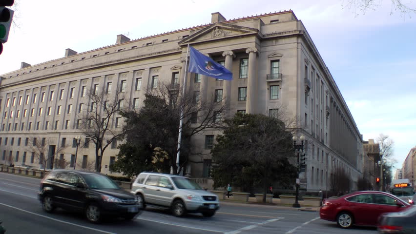 Headquarters of the U.S. Justice Department in Washington, DC.  Renamed Robert F. Kennedy Department of Justice Building in 2001. No recognizable pedestrians.  Blue flag is the Dept. of Justice flag.
