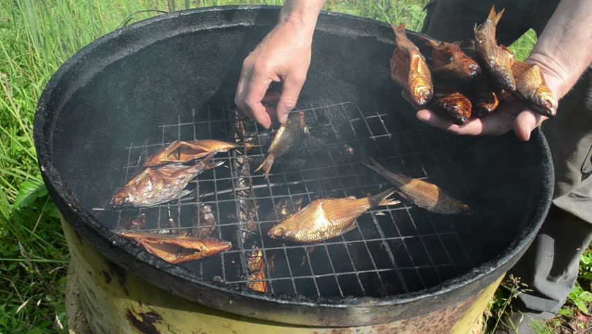 hand take fresh delicacy smoked fish from smokehouse.