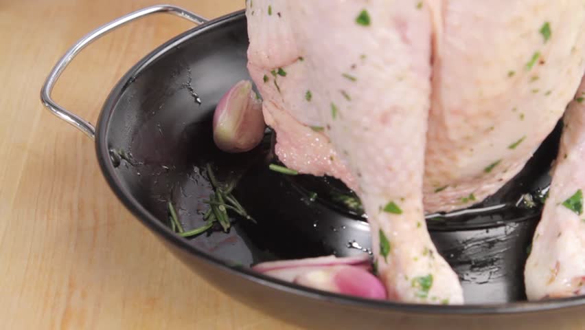 Shallots with olive oil and rosemary being added to a chicken roaster