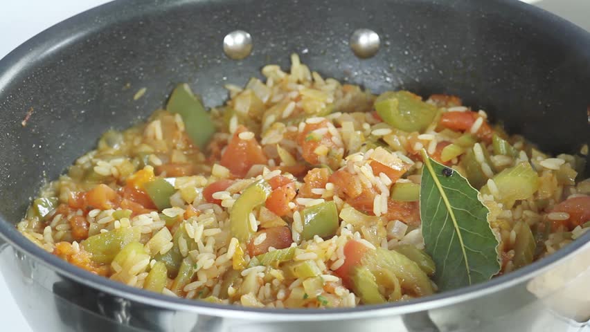 Jambalaya being made: sliced sausages and prawns being added to a rice and vegetable stew