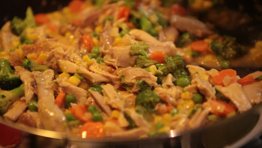 Cooking chicken pot pie filling on pan stirring with spatula close up
