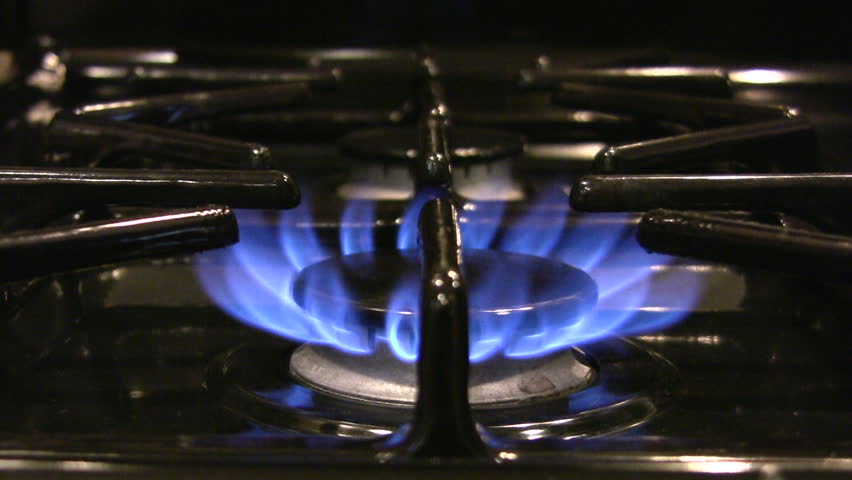 HD 1080i shot of a stainless steel pot placed over the blue flame of a gass stove.