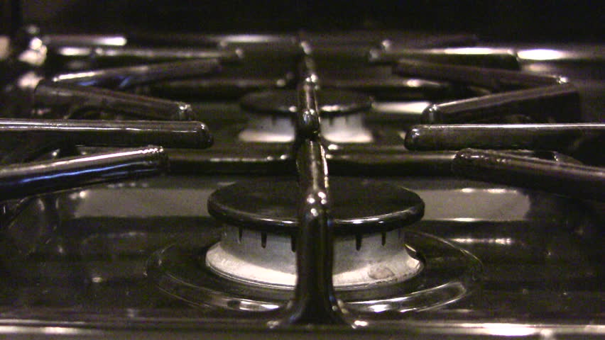 HD 1080i shot of a gas stove igniting, with a pot placed over the top, and then shutting of as the pot is removed.