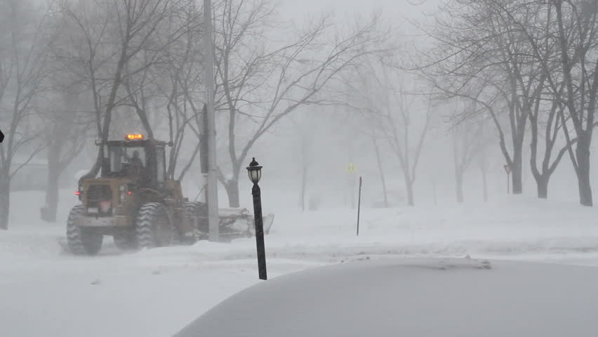 snow plow cleaning street in a snowstorm in Sorel-Tracy town, Quebec province. Canada at winter.