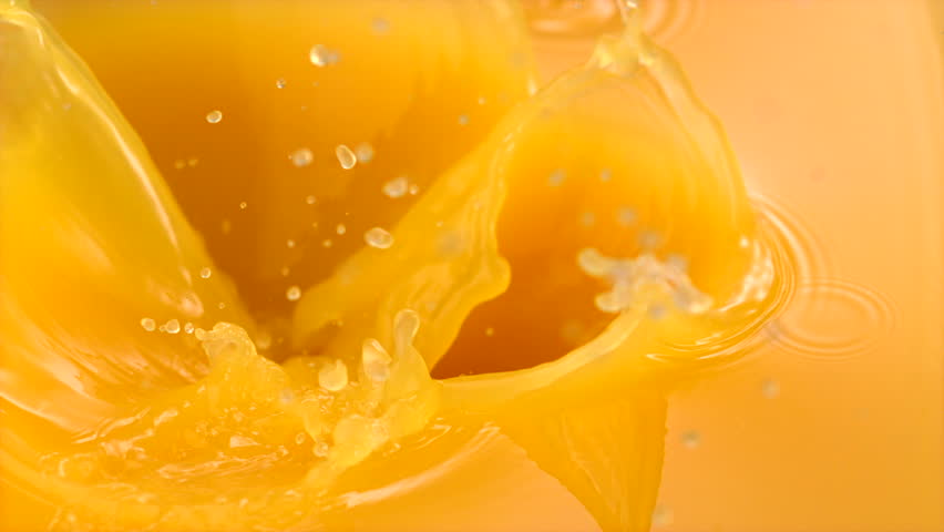 Sliced orange falling into orange juice shooting with high speed camera.