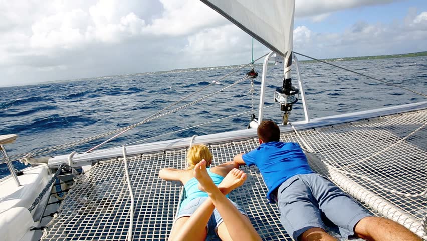 Couple relaxing on catamaran net looking at the sea