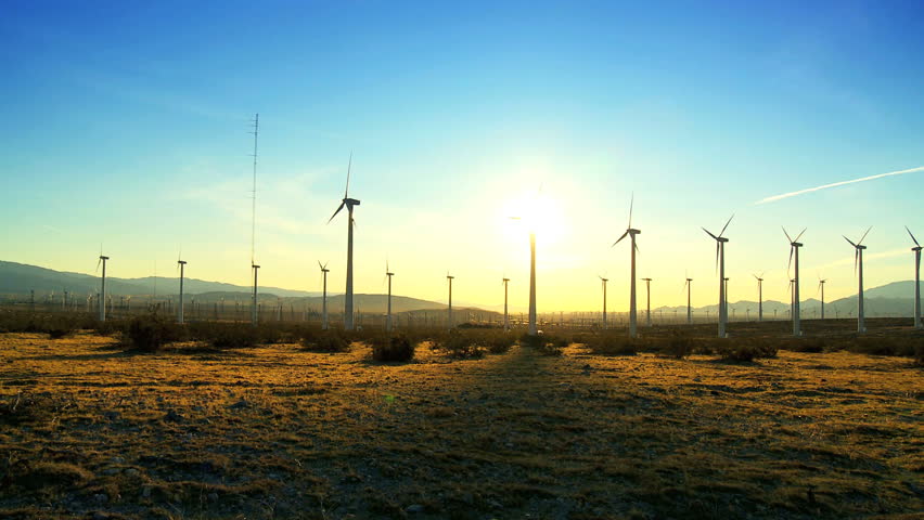 Wind turbines producing clean alternative energy in silhouette at sunset
