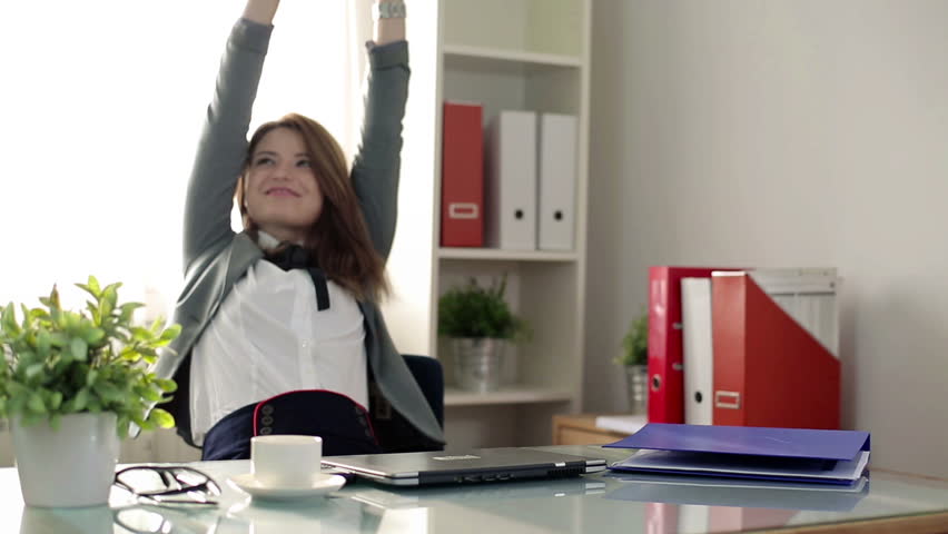 Businesswoman finishing work on laptop and relaxing in office
