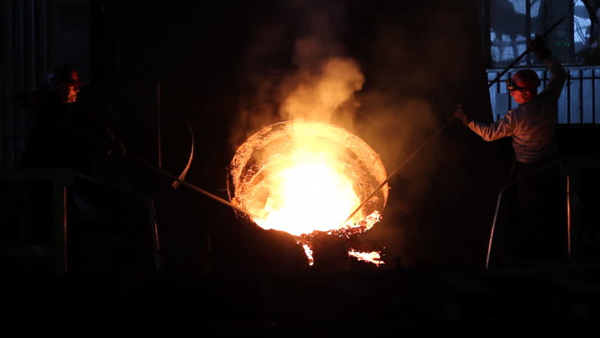 Hard work in the foundry, workers controlling iron smelting in furnaces, too hot and smoky working environment