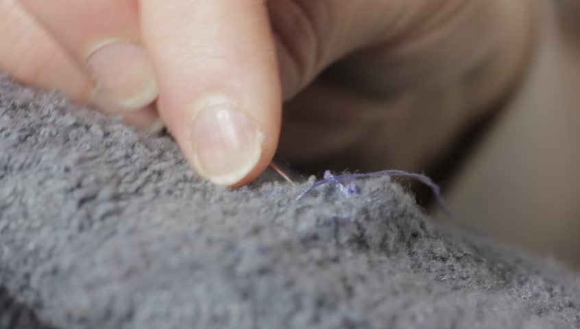 Woman stitching fabric by hand close up