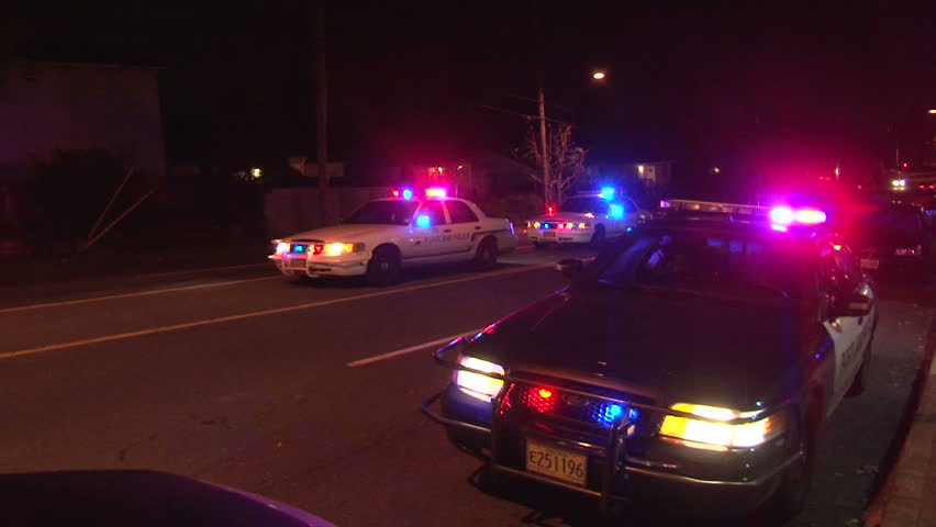 PORTLAND, OREGON - CIRCA DECEMBER 2012: Police lights flashing at night downtown at crime scene, zoom out.
