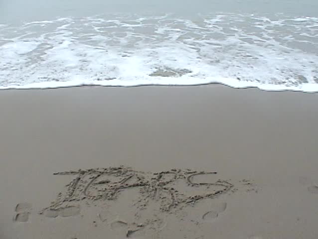 the word TEARS is washed away by the tide on the beach