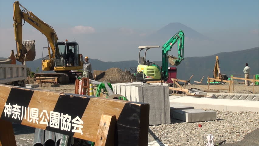 HAKONE, JAPAN - 16 OCTOBER 2012: Construction work on a road is proceeding with the magnificent Mount Fuji in the background, providing for an interesting contrast, in Hakone, Japan