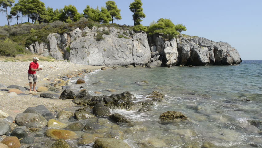 Male skimming stones on a beach