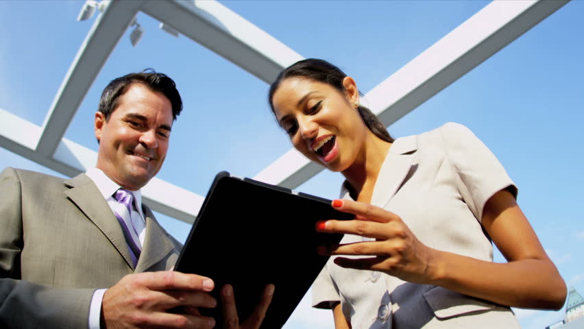 Successful team of diverse financial managers working on touch screen technology on city rooftop