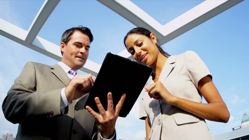 Caucasian successful businessman starting meeting with Hispanic woman handshake using online touch screen on rooftop