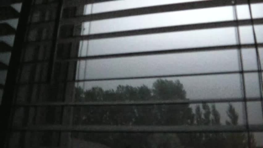 Lightning strikes abundantly through white window blinds in darkened room during summer night.